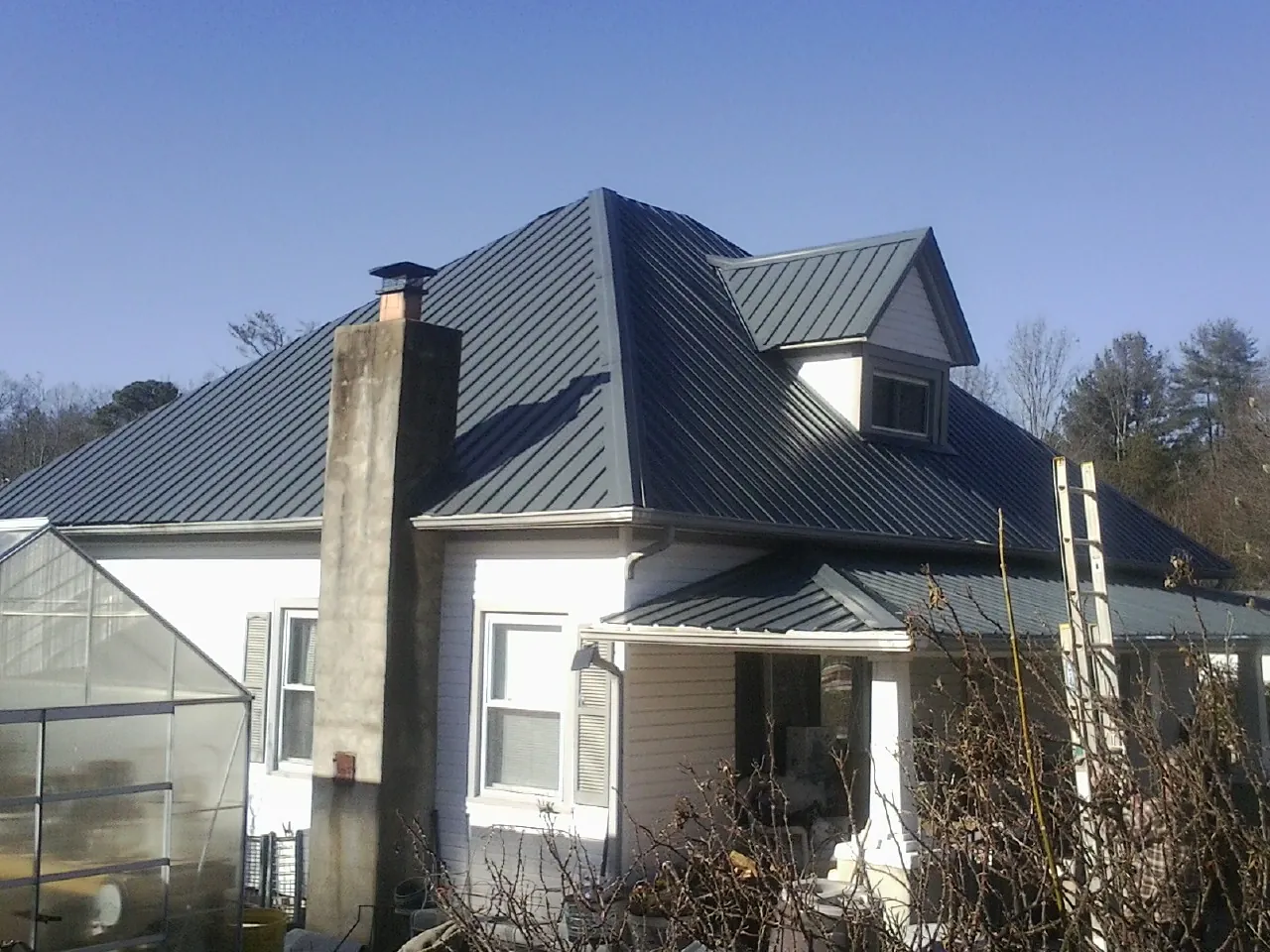 Dark blue standing seam metal roof on a white farmhouse with dormer — Slate & Tile Roof Repair by Roofing Brothers in Ansonia