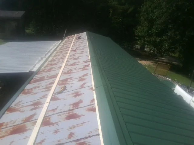 Old rusted panels beside newly installed green metal roofing — Wind Damage Roof Repair by Roofing Brothers in Ansonia